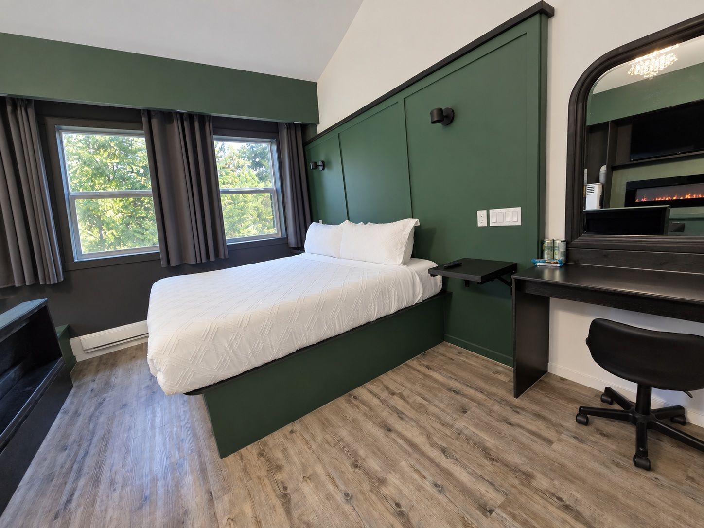 Una habitación de hotel con cama, escritorio, silla y chimenea.