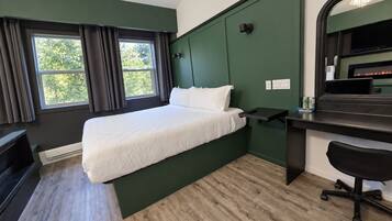 Una habitación de hotel con cama, escritorio, silla y chimenea.