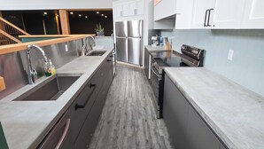 A modern kitchen with stainless steel appliances, a wooden floor, and white cabinetry. - Copper Rose Retreat B&B (Invermere)