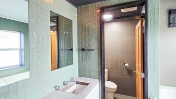 Une salle de bain moderne avec un meuble-lavabo à deux vasques, des toilettes et un espace douche.