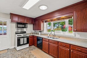 A kitchen with wooden cabinets, a stove, microwave, and dishwasher.