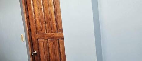 A wooden door with a simple handle and a keyhole, set in a plain wall.