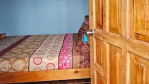 A room with a bed, a wooden door, and patterned tiles on the floor. - Hostal Casa Maricel (Granada)