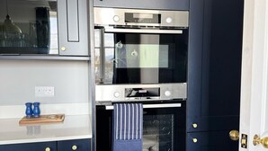 Een keuken met donkere kastjes, een Bosch oven en een houten snijplank op het aanrecht.