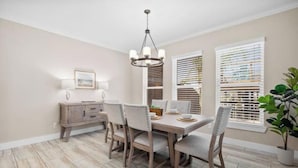 A dining area with a wooden table, four chairs, a chandelier, a sideboard, and a potted plant. - Laguna Getaway Boater & Pet Friendly Canal Home (Corpus Christi)