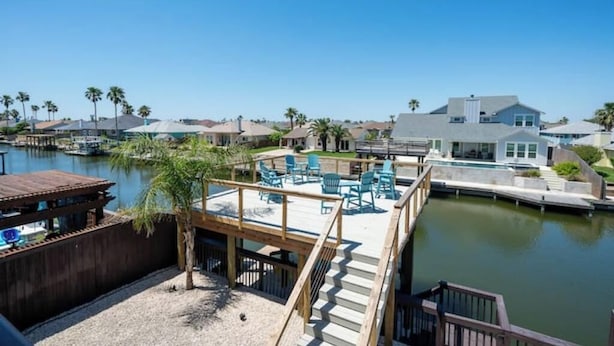 A waterfront property with a wooden deck, outdoor seating, and a view of the marina. - Laguna Getaway Boater & Pet Friendly Canal Home (Corpus Christi)