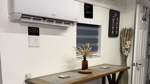 A small dining area with a wooden table and bench, an air conditioner, a window, and a wall-mounted sign. - Sol studio in the middle of Miami (Miami)
