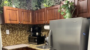 A kitchen with wooden cabinets, a stainless steel refrigerator, a coffee maker, and a microwave. - Sol studio in the middle of Miami (Miami)