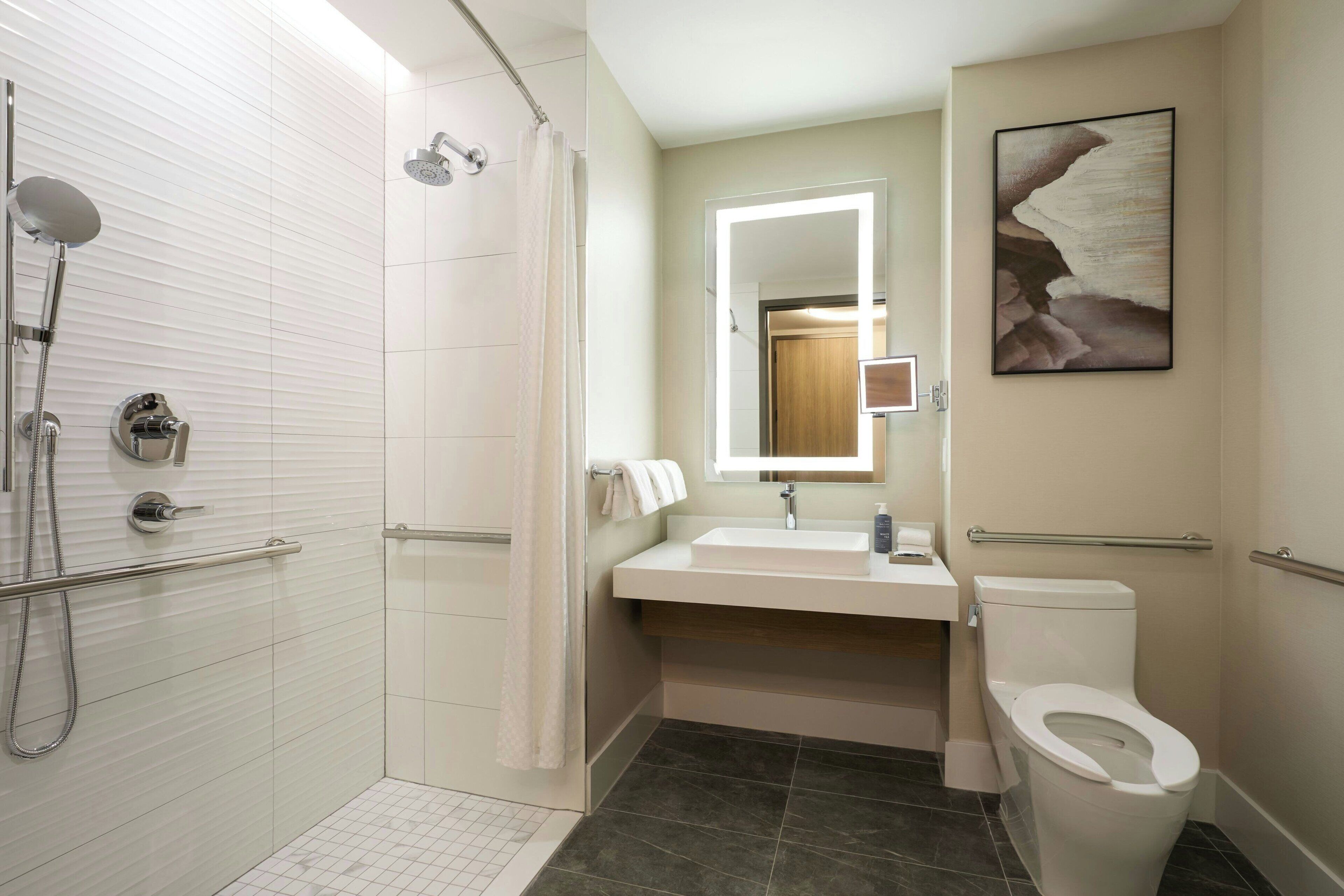Une salle de bain moderne avec une douche à l’italienne, un lavabo avec un miroir et des toilettes.
