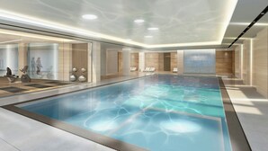 Una piscina interior moderna con agua cristalina, rodeada de paredes de vidrio y paneles de madera.