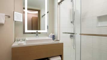 Une salle de bain moderne avec un lavabo blanc, un miroir et une douche.