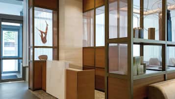 A modern reception area with a wooden reception desk, a glass partition, and a view of the outdoors.