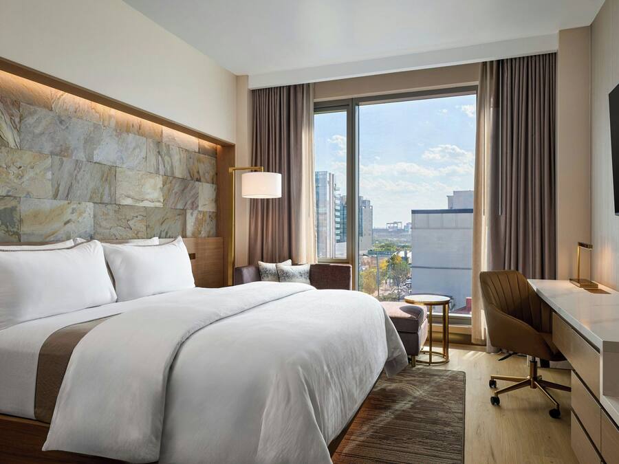 Habitació d'hotel moderna amb un llit gran, un escriptori i vistes a la ciutat.
