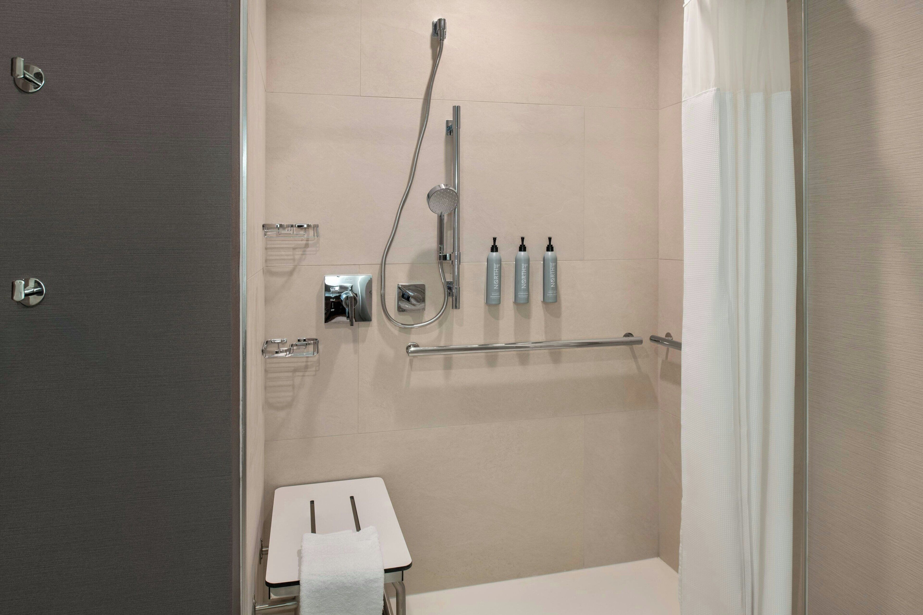 Un baño moderno con ducha, un perchero y una pequeña mesa con una toalla.