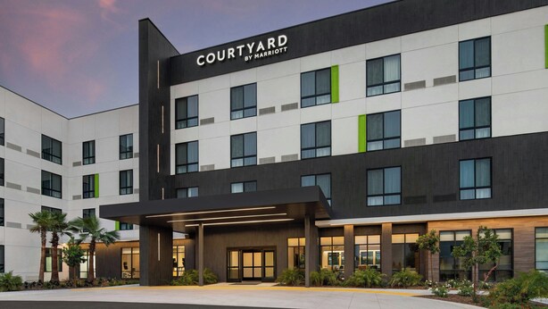 A modern Courtyard by Marriott hotel with a symmetrical facade, large windows, and a landscaped entrance area. - Courtyard By Marriott San Bernardino Loma Linda (Loma Linda)