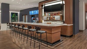 A modern bar area with a long counter, multiple stools, and a television screen. - Courtyard By Marriott San Bernardino Loma Linda (Loma Linda)