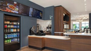 A modern hotel lobby with a self-service beverage station, a coffee machine, and a menu display. - Courtyard By Marriott San Bernardino Loma Linda (Loma Linda)