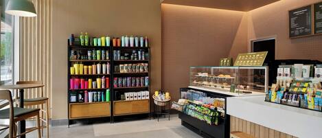 A modern coffee shop interior with a counter, seating area, and a variety of products on shelves.