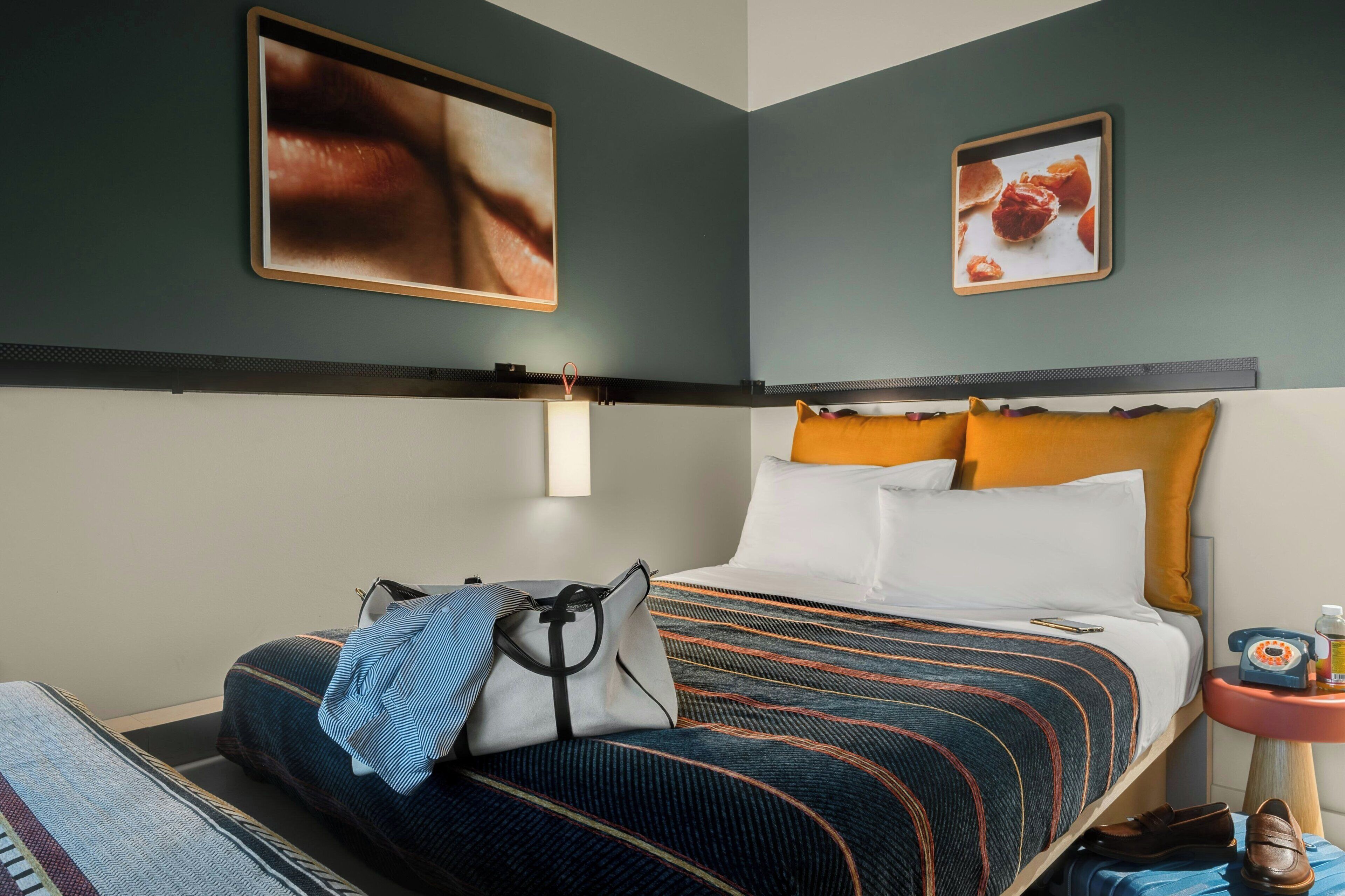A hotel room with a bed, a nightstand, a lamp, and a framed picture on the wall.