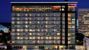 A multi-story hotel with a modern facade, large windows, and a neon sign.