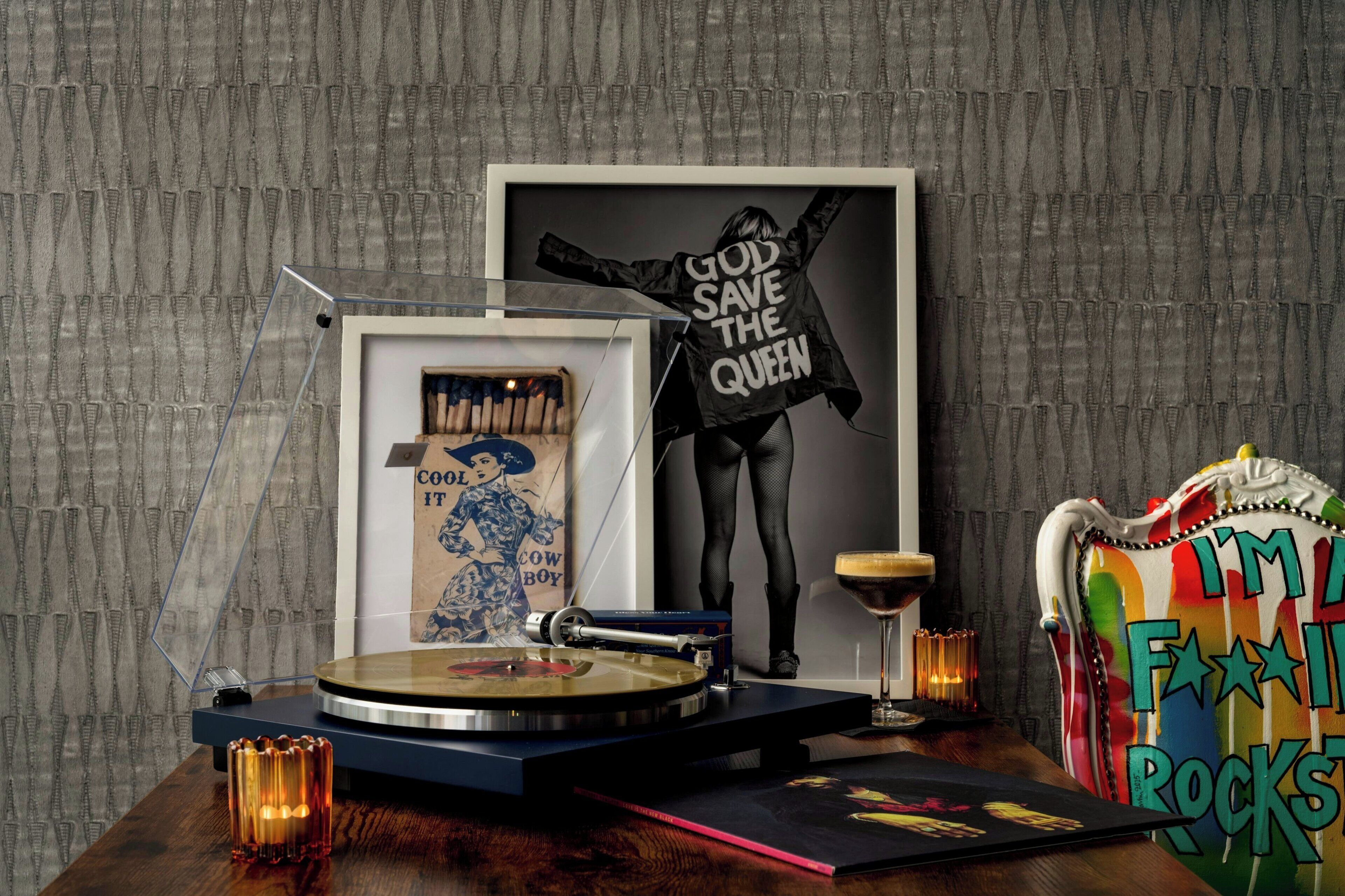A room with a turntable, framed posters, a colorful chair, and a decorative wall.