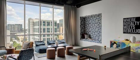 Un área de descanso moderna con mesa de ping pong, asientos y vista a la ciudad.