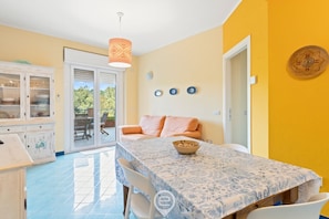 A dining area with a table set for two, a sofa, and a cabinet with glass doors. - Pine & Sea Hideaway - Torre Grande (Torre Grande)