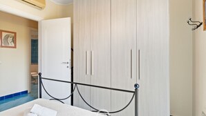 A bedroom with a bed, a wardrobe, and a bathroom visible through an open door. - Pine & Sea Hideaway - Torre Grande (Torre Grande)