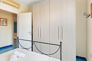 Un dormitorio con cama, armario y baño visible a través de una puerta abierta.