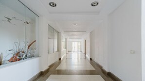 A long, narrow hallway with white walls and a tiled floor, leading to a bright room at the end. - Pine & Sea Hideaway - Torre Grande (Torre Grande)