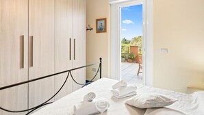 A bedroom with a bed, a wooden wardrobe, and a view of the outdoors. - Pine & Sea Hideaway - Torre Grande (Torre Grande)