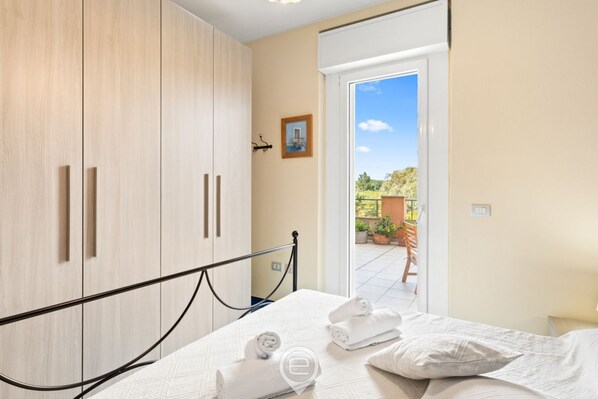 A bedroom with a bed, a wooden wardrobe, and a view of the outdoors. - Pine & Sea Hideaway - Torre Grande (Torre Grande)