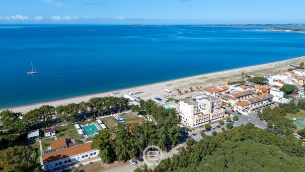 An aerial view of a coastal town with a beach, buildings, and a sailboat on the water. - Pine & Sea Hideaway - Torre Grande (Torre Grande)