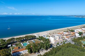 An aerial view of a coastal town with a beach, buildings, and a sailboat on the water. - Pine & Sea Hideaway - Torre Grande (Torre Grande)