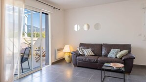 A modern living room with a leather sofa, a glass table, and a lamp. - Casa Verde (San-Nicolao)