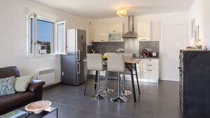 A modern kitchen with a dining area, a refrigerator, and a coffee machine. - Casa Verde (San-Nicolao)