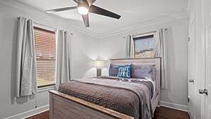 A bedroom with a wooden bed, a ceiling fan, and a window with blinds. - Charming Bungalow with Spacious Yard (Overland Park)