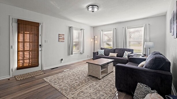 A modern living room with a sectional sofa, a coffee table, and a patterned rug. - Charming Bungalow with Spacious Yard (Overland Park)