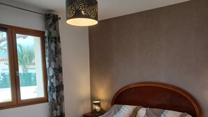 A neatly made bed with white linens, a wooden headboard, and a bedside table with a lamp. - Less than 10 minutes from the ocean! 5-Bedroom Family Villa with Air Conditioning, Wi-Fi, and a Pool (Claira)