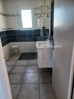A bathroom with a white sink, a glass shower enclosure, and a small white stool. - Less than 10 minutes from the ocean! 5-bedroom family villa with air conditioning, Wi-Fi, and a pool (Claira)