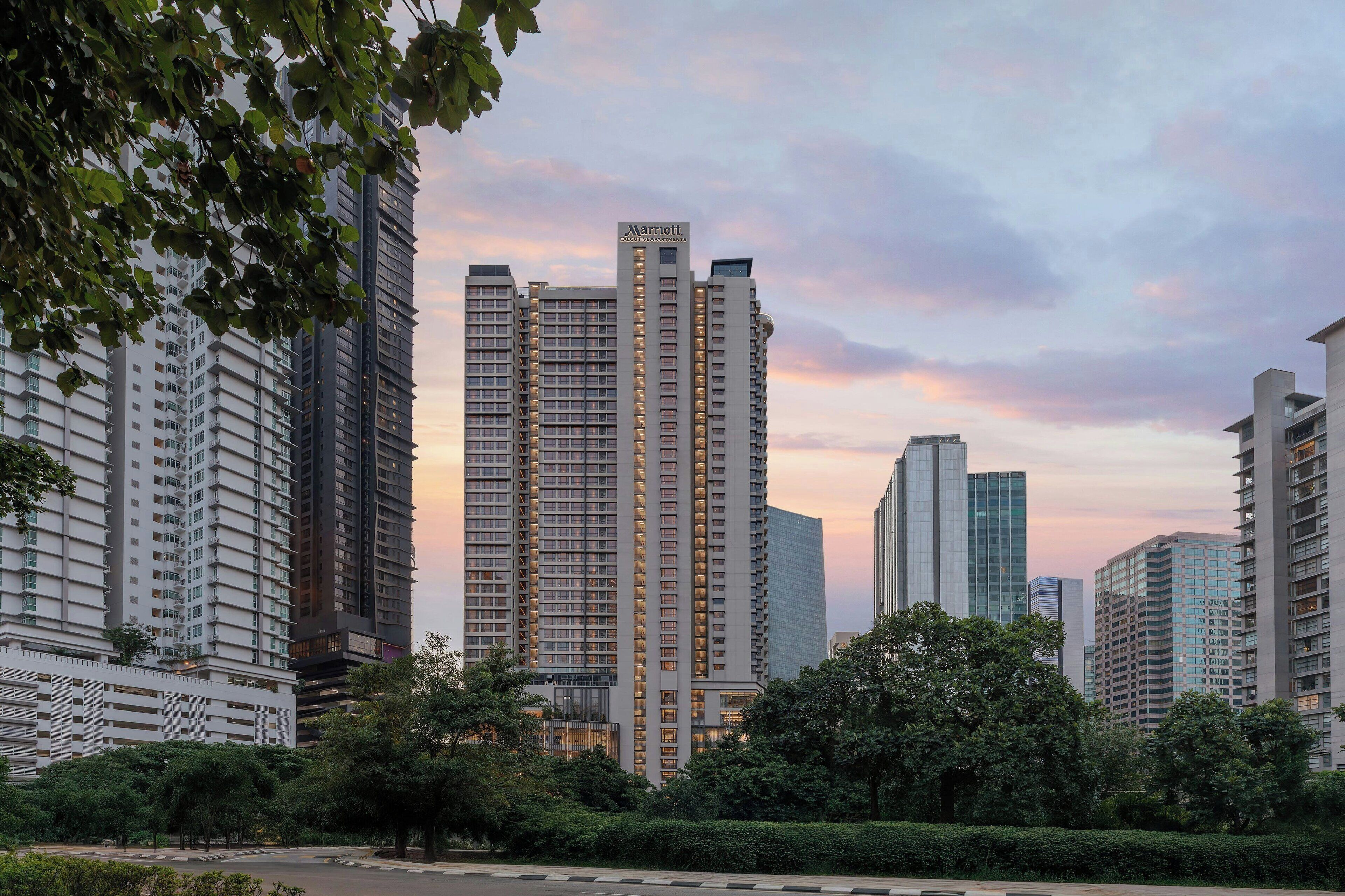 A high-rise building with a Marriott sign, surrounded by other tall buildings and greenery.