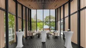 A modern indoor space with a wooden deck, large windows, and a central table with chairs. - Marriott Executive Apartments Kuala Lumpur (Kuala Lumpur)