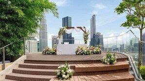 A rooftop venue with a wooden stage, floral arrangements, and a city skyline in the background. - Marriott Executive Apartments Kuala Lumpur (Kuala Lumpur)