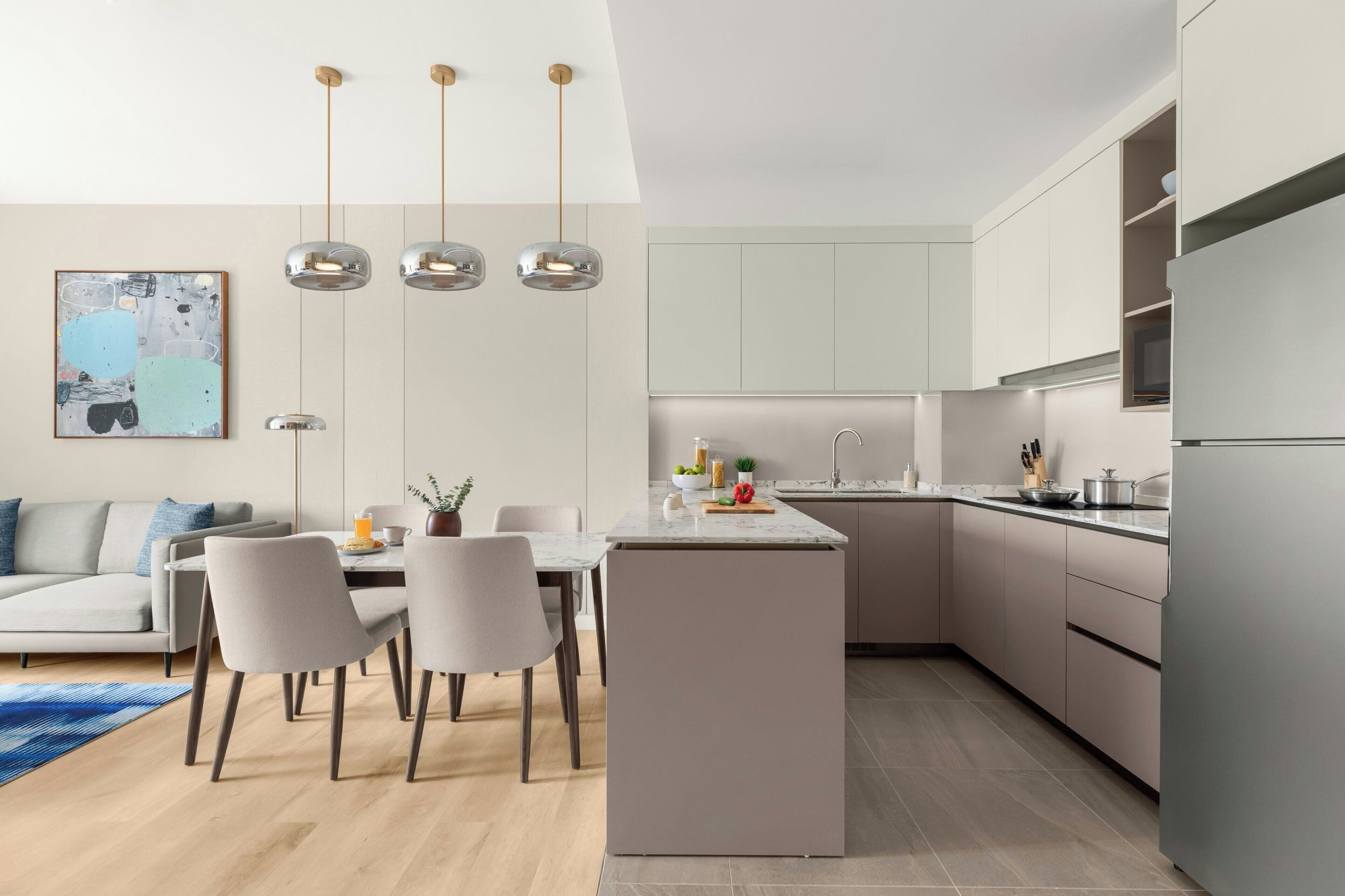 A modern kitchen with a central island, pendant lighting, and a dining area with a sofa and chairs.