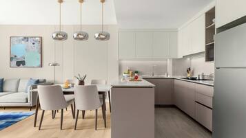 A modern kitchen with a central island, pendant lighting, and a dining area with a sofa and chairs.