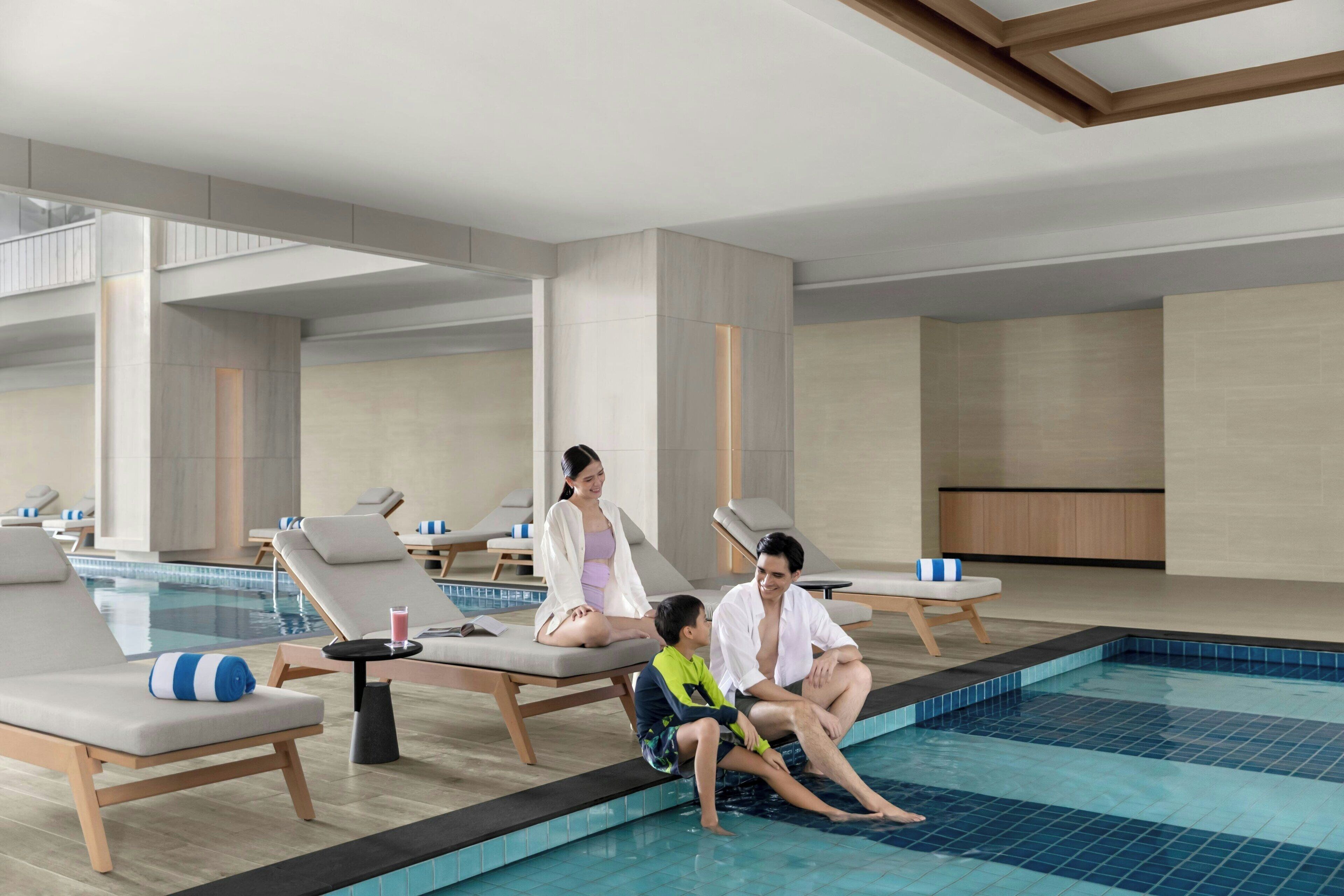 A modern indoor pool area with lounge chairs and a pool.