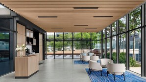 A modern hotel lobby with a reception desk, seating area, and large windows offering views of the outdoors. - Marriott Executive Apartments Kuala Lumpur (Kuala Lumpur)