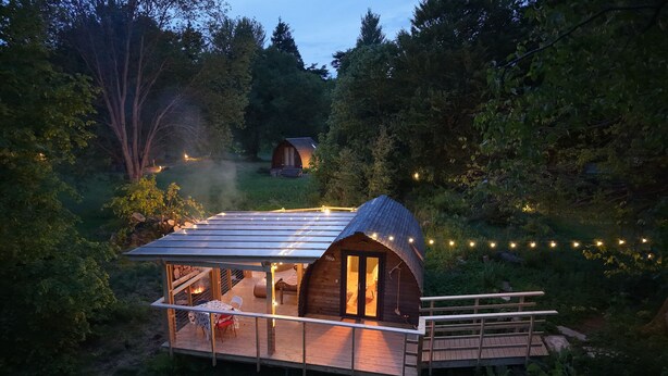 Une cabane confortable avec un toit en métal, une terrasse et un foyer extérieur.