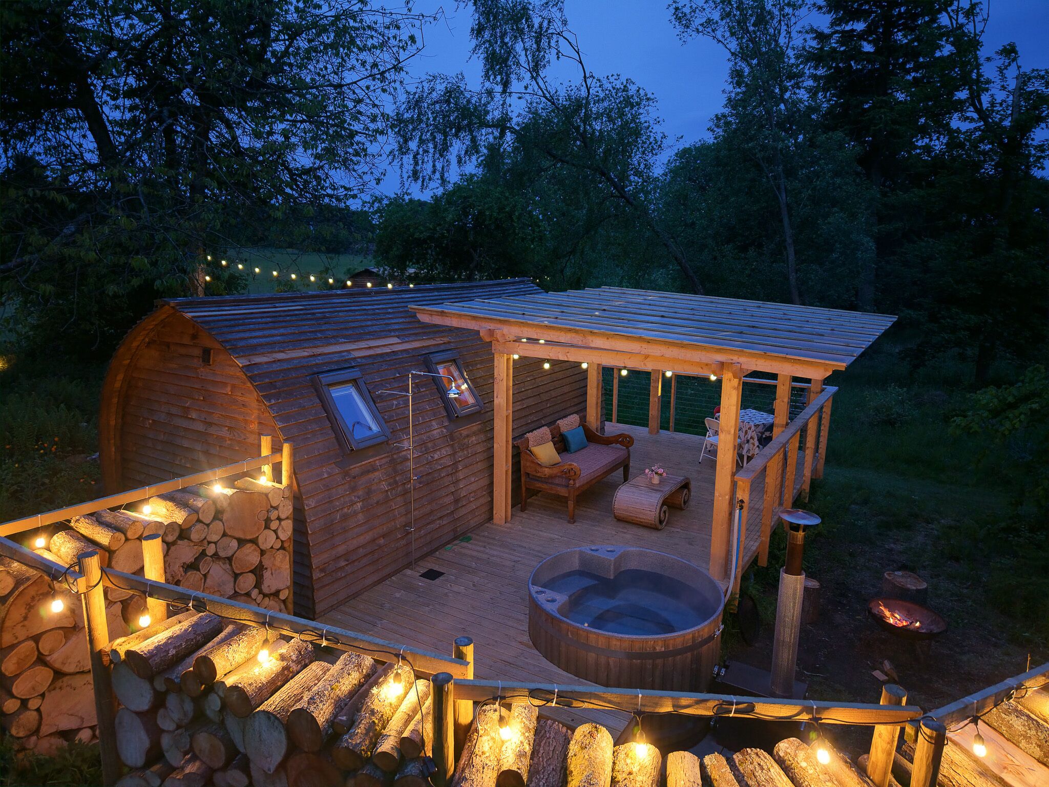En mysig stuga med ett bubbelbad, en träveranda och ljusslingor.