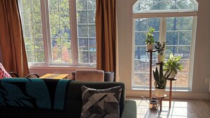 Una sala de estar con un sofá verde, una mesa de centro y una ventana con cortinas.